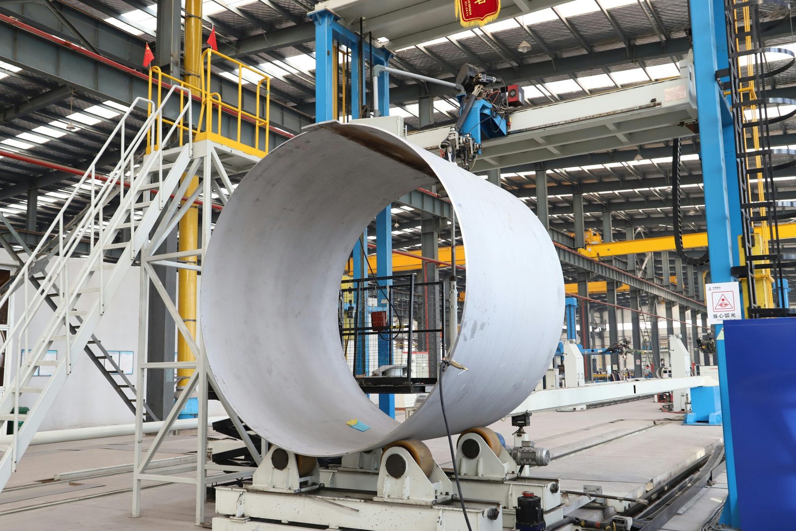 A spacious industrial factory scene showcasing steel pipe production with modern machinery.